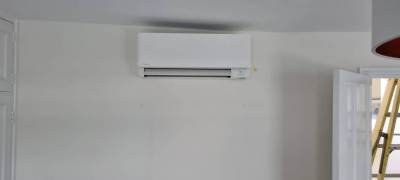 A slimline wall-mounted indoor unit in a white living room